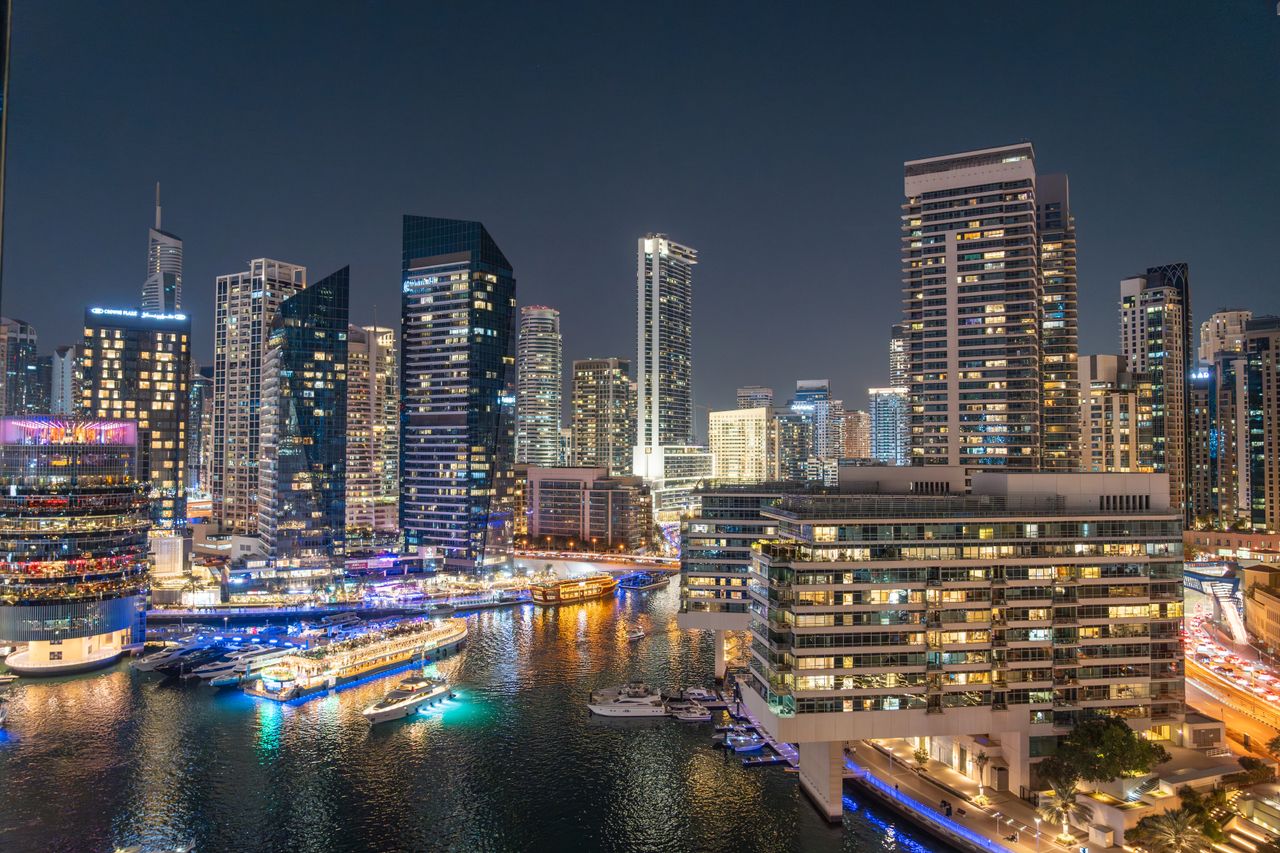 Offerings Stunning night view of Dubai Marina with illuminated skyscrapers and reflections on the water.
