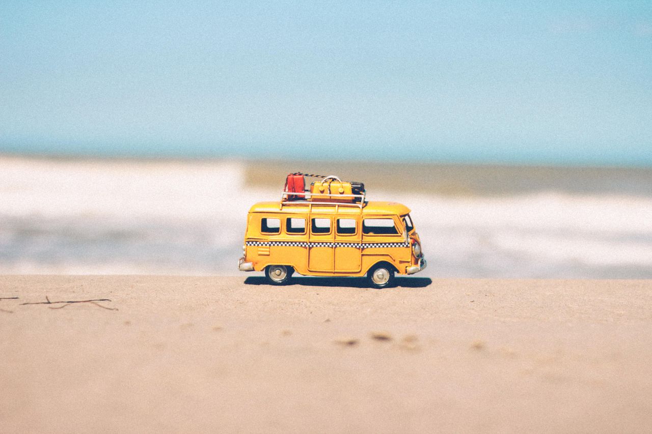 Crafting Captivating Headlines: Your awesome post title goes here A vibrant yellow toy van sits on a sandy beach with an ocean backdrop, symbolizing fun travel adventures.